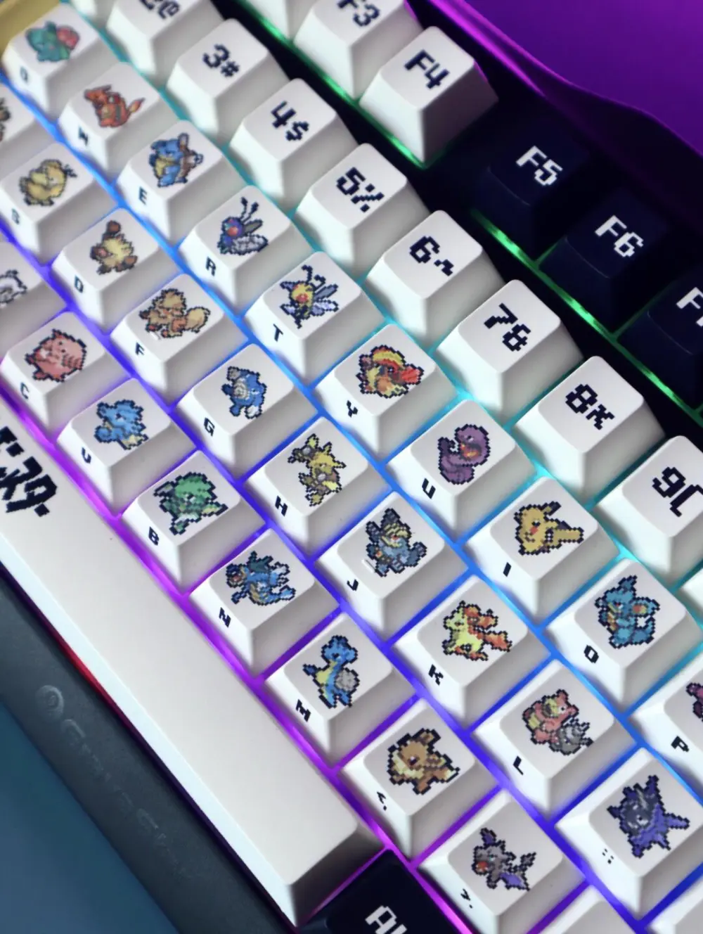 Close-up of Pokemon Red and Green pixel art keycaps on an RGB mechanical keyboard showing first-gen characters.