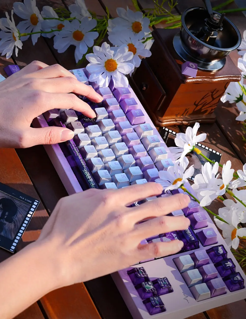 Chainsaw Man Reze Keycaps Typing Setup Person typing on Chainsaw Man Reze metallic coated keycaps on a wooden table with daisies.