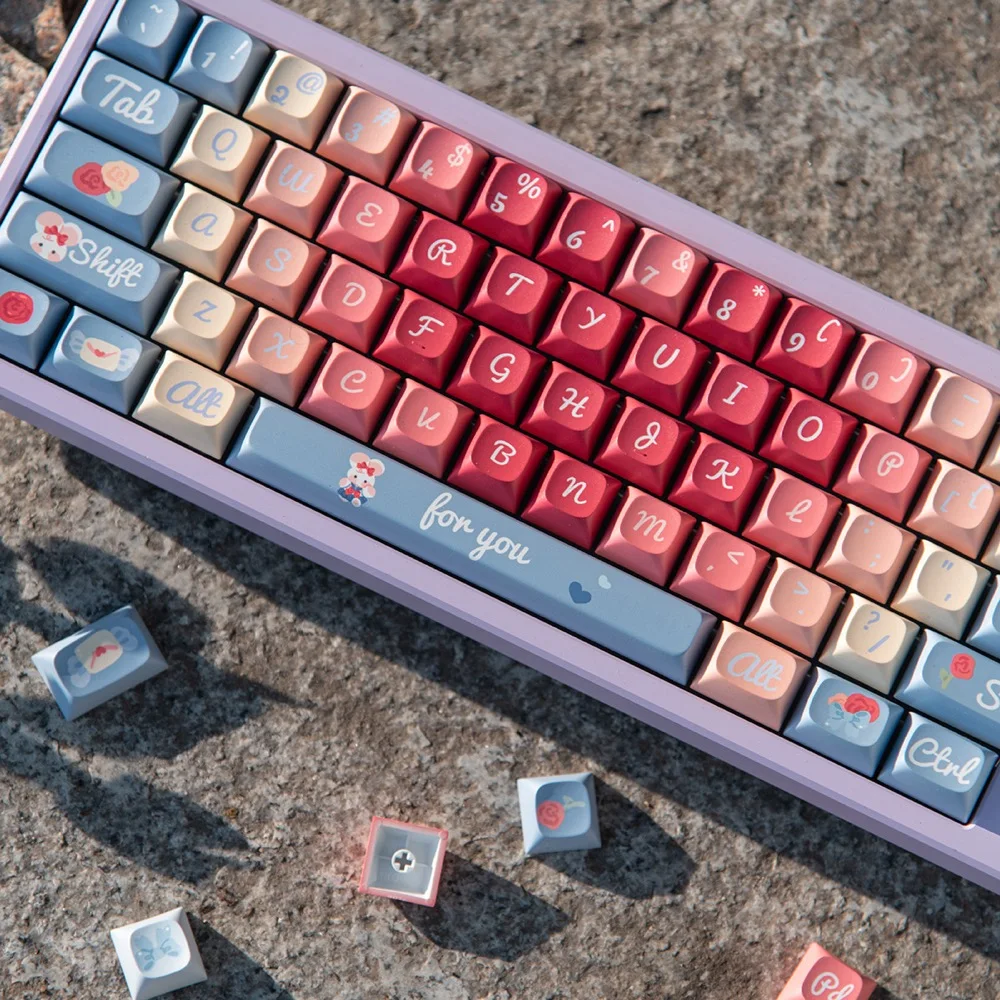 Roses Poem PBT keycaps on stone surface with loose keycaps scattered around the keyboard in a lifestyle flat lay