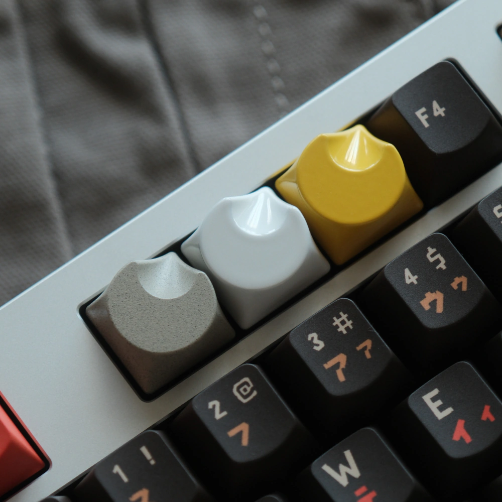 Close-up of grey, white, and yellow aluminum keycaps in a crescent moon shape on a keyboard.