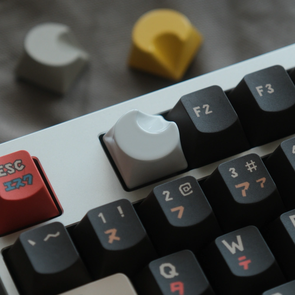 The white crescent-shaped aluminum art keycaps placed beside the standard keys of the mechanical keyboard.