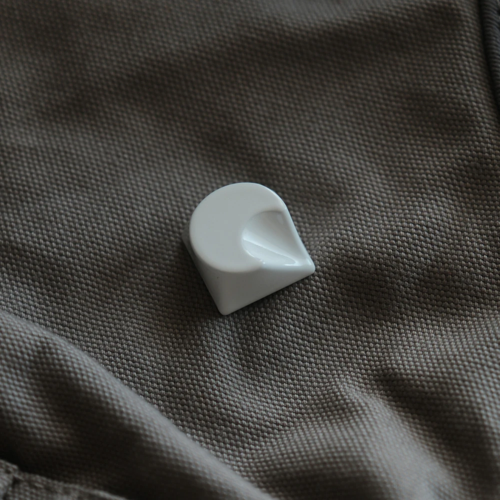 White artisan aluminum keycap with crescent moon design resting on grey woven material.