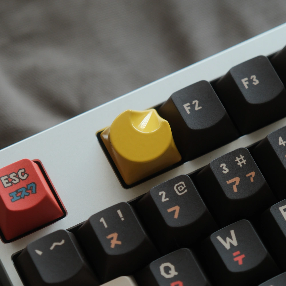 Yellow CNC-machined aluminum artisan keycap with a crescent moon shape on a keyboard.