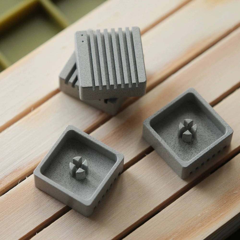 Grey Heatsink Metal Artisan Keycaps Bottom View Linen grey heatsink metal artisan keycaps resting on a wooden surface, showing bottom stem mounts.