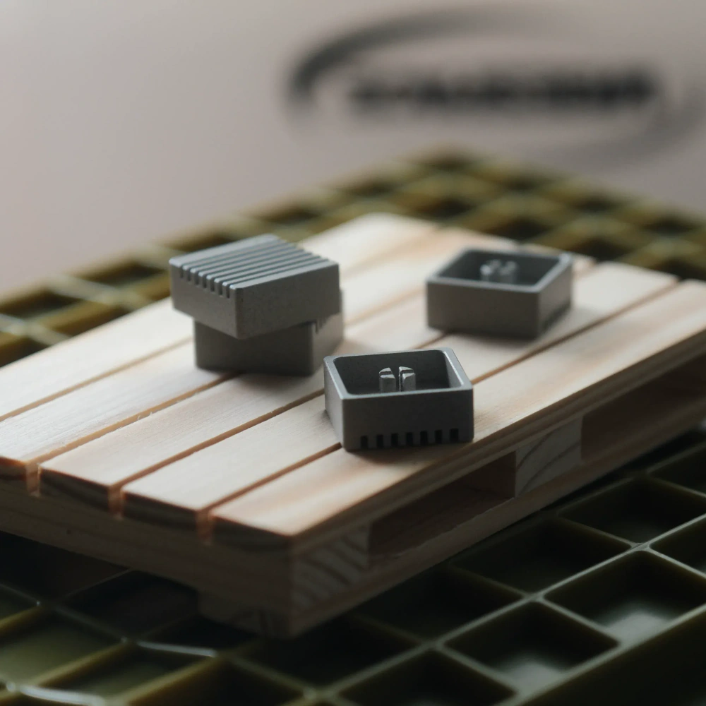 Linen Grey Heatsink Metal Artisan Keycaps Four linen grey CNC aluminum heatsink metal artisan keycaps resting on a miniature wooden pallet.
