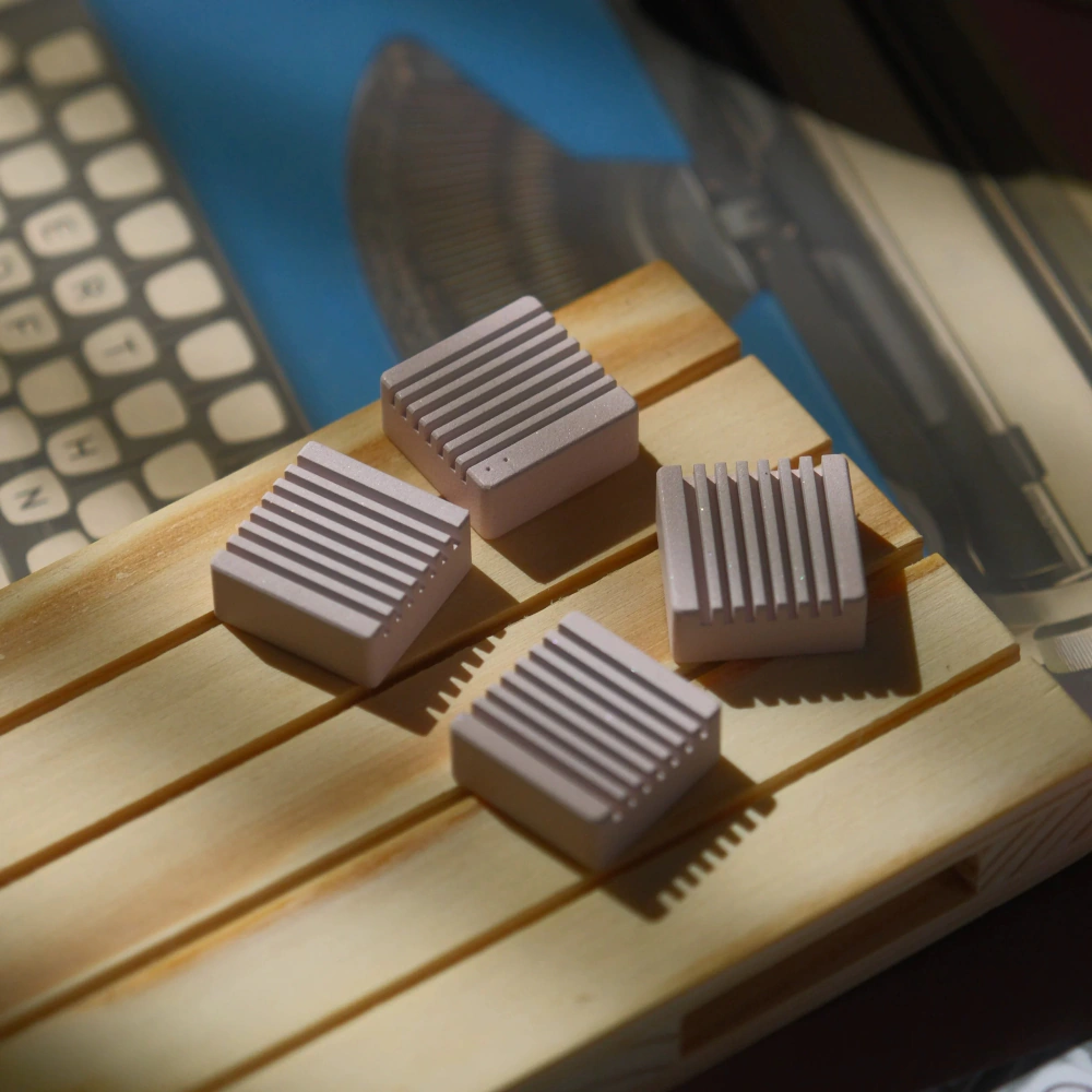 Heatsink Arrow Keys Wood Display Four ribbed metal artisan keycaps resting on a wooden display board in sunlight.