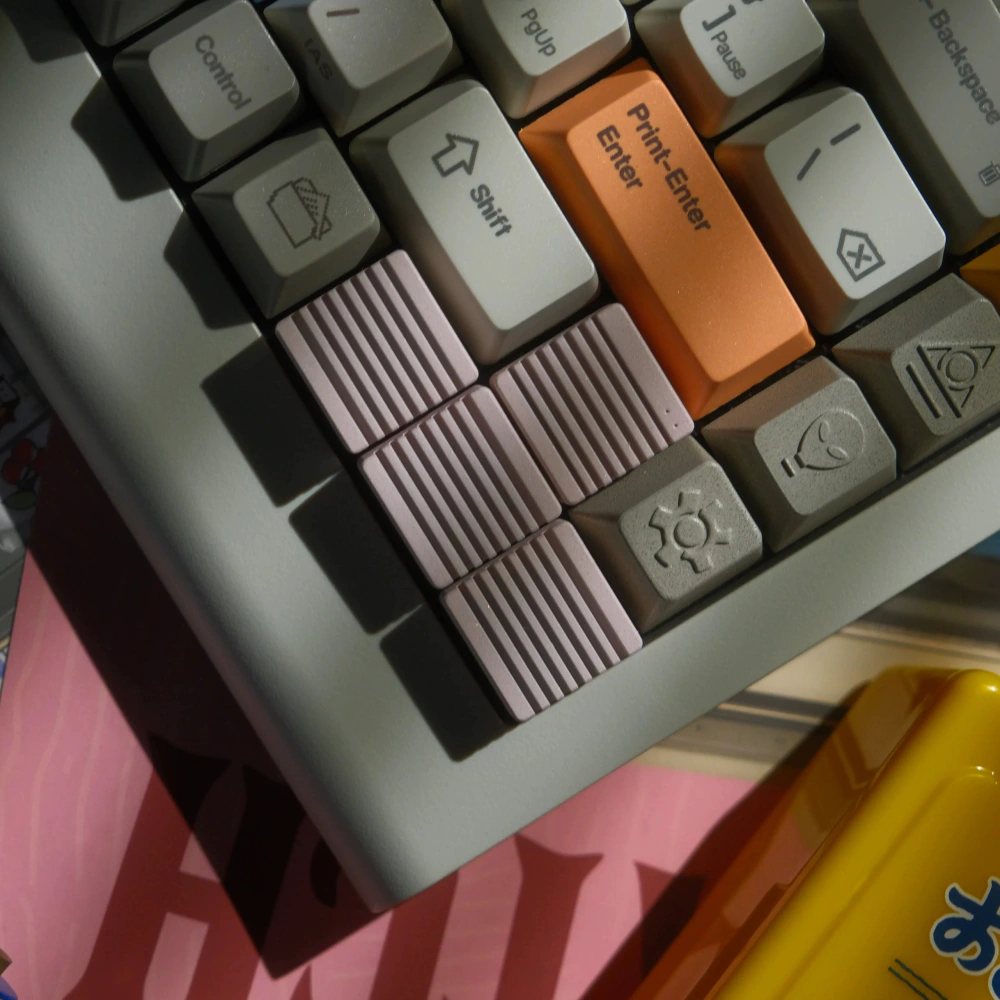 Sakura Pink Heatsink Arrow Keycaps Close-up of four pink ribbed metal artisan keycaps on a keyboard arrow cluster.