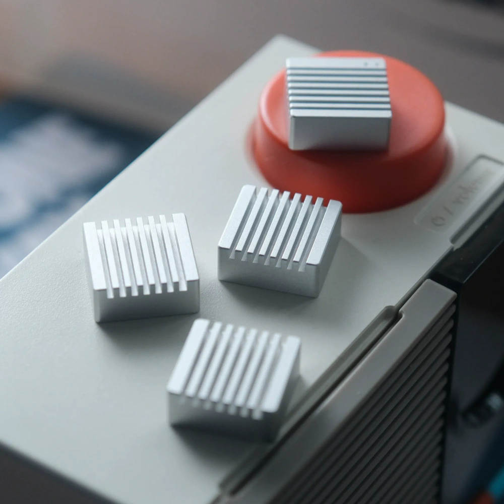 Silver Heatsink Metal Artisan Keycaps Set Set of four streaming silver metal artisan keycaps with ribbed heatsink design displayed on a retro device.
