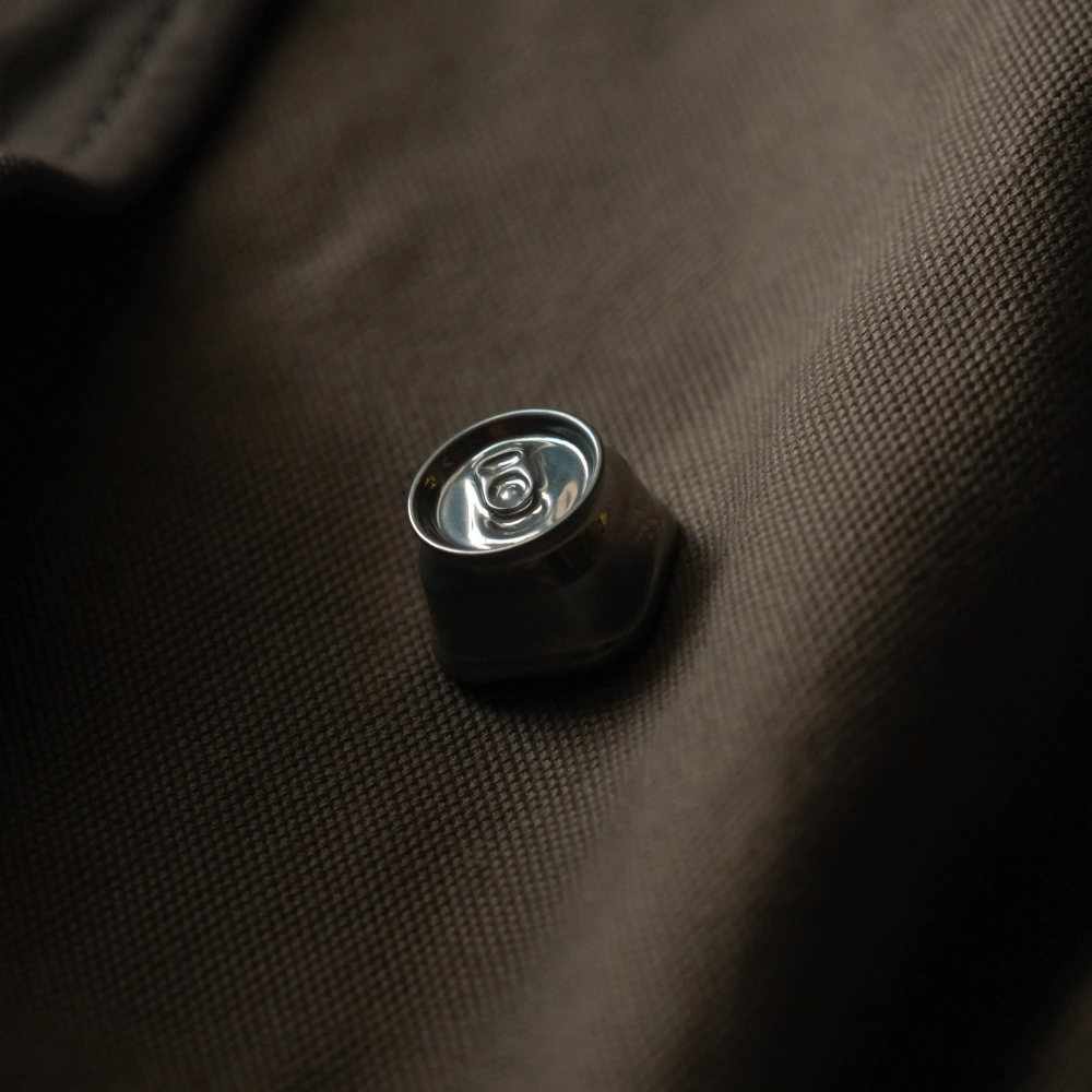 Custom metal craft keycaps similar to flattened soda cans are placed on textured brown material.