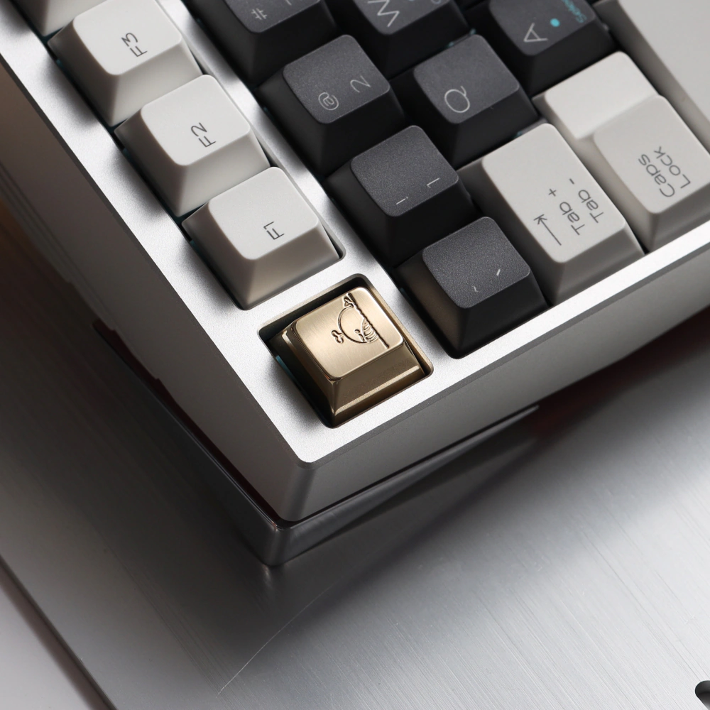 Cute whale mirror polished brass keycap mounted on the ESC key of a silver keyboard.