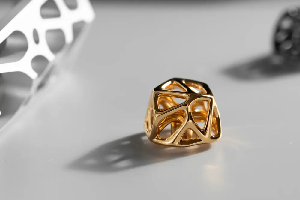 Futuristic Gold Hollow Metal Artisan Keycap Gold hollow metal artisan keycap with an organic cell lattice design on a grey surface.