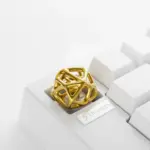 Gold futuristic hollow metal artisan keycap with an organic cell lattice design on a white keyboard.