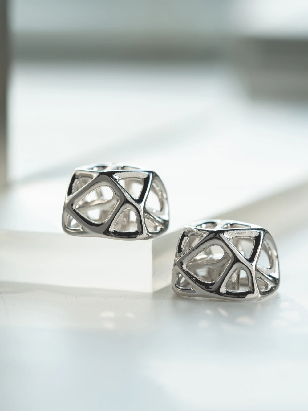 Futuristic Hollow Platinum Artisan Keycap Futuristic handcrafted hollow metal artisan keycaps in platinum finish resting on an acrylic block.