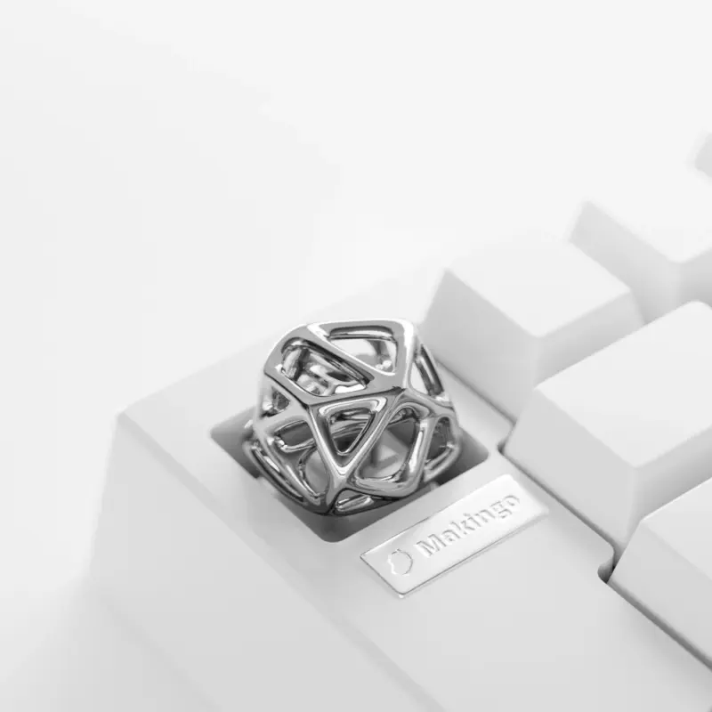Silver hollow platinum artisan keycap with geometric metal lattice installed on a white mechanical keyboard.