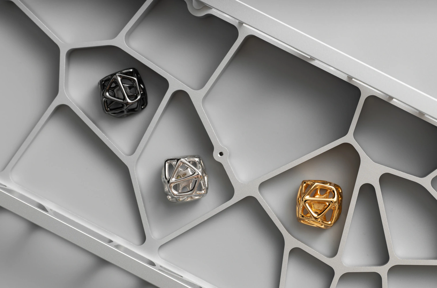 Hollow Metal Artisan Keycap Colors Platinum, gold, and black gold hollow artisan keycaps with an organic cell lattice design resting in a metal tray.