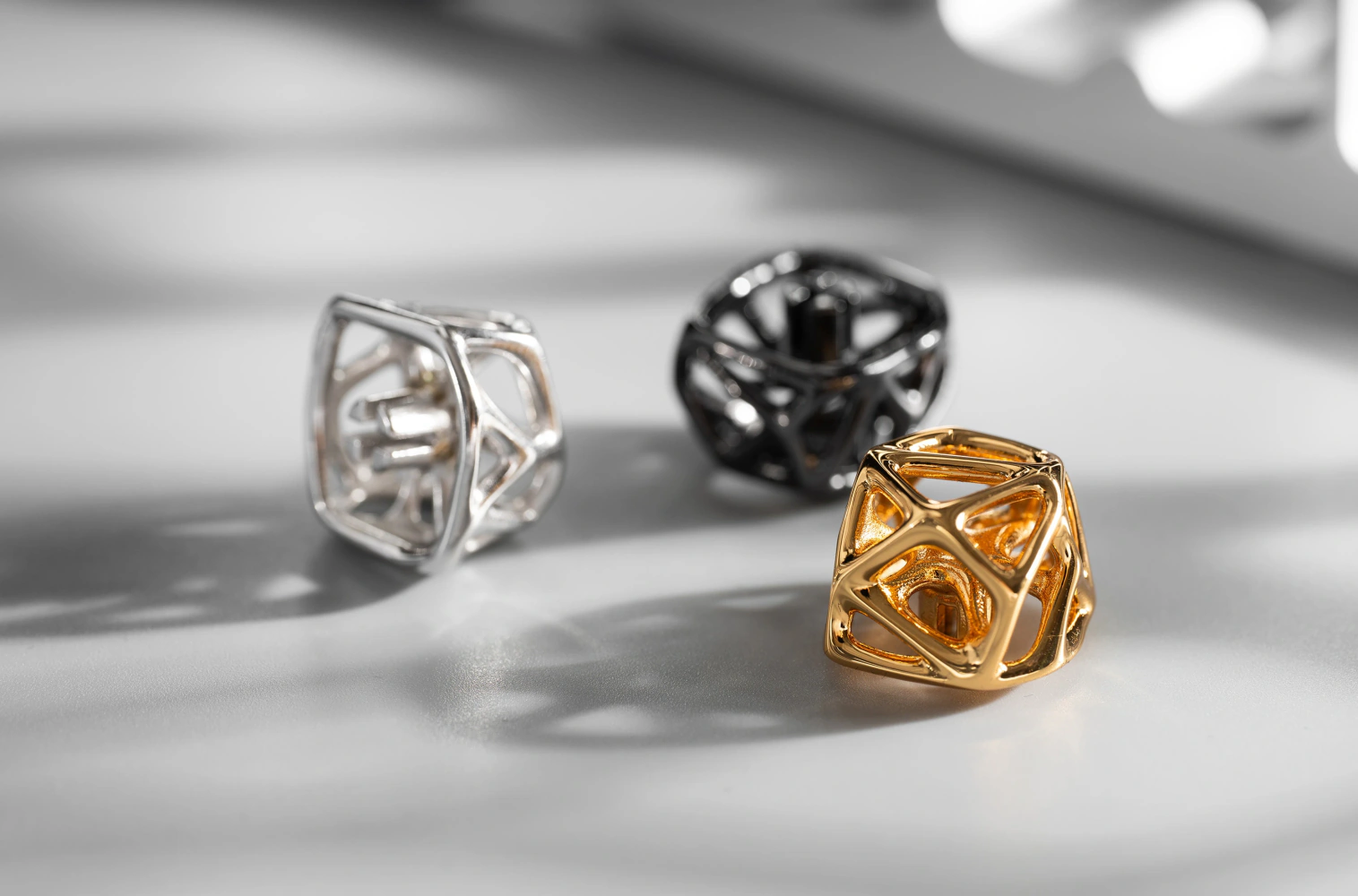 Hollow Metal Artisan Keycaps in Three Colors Group of three futuristic hollow metal artisan keycaps in gold, platinum, and black finishes.