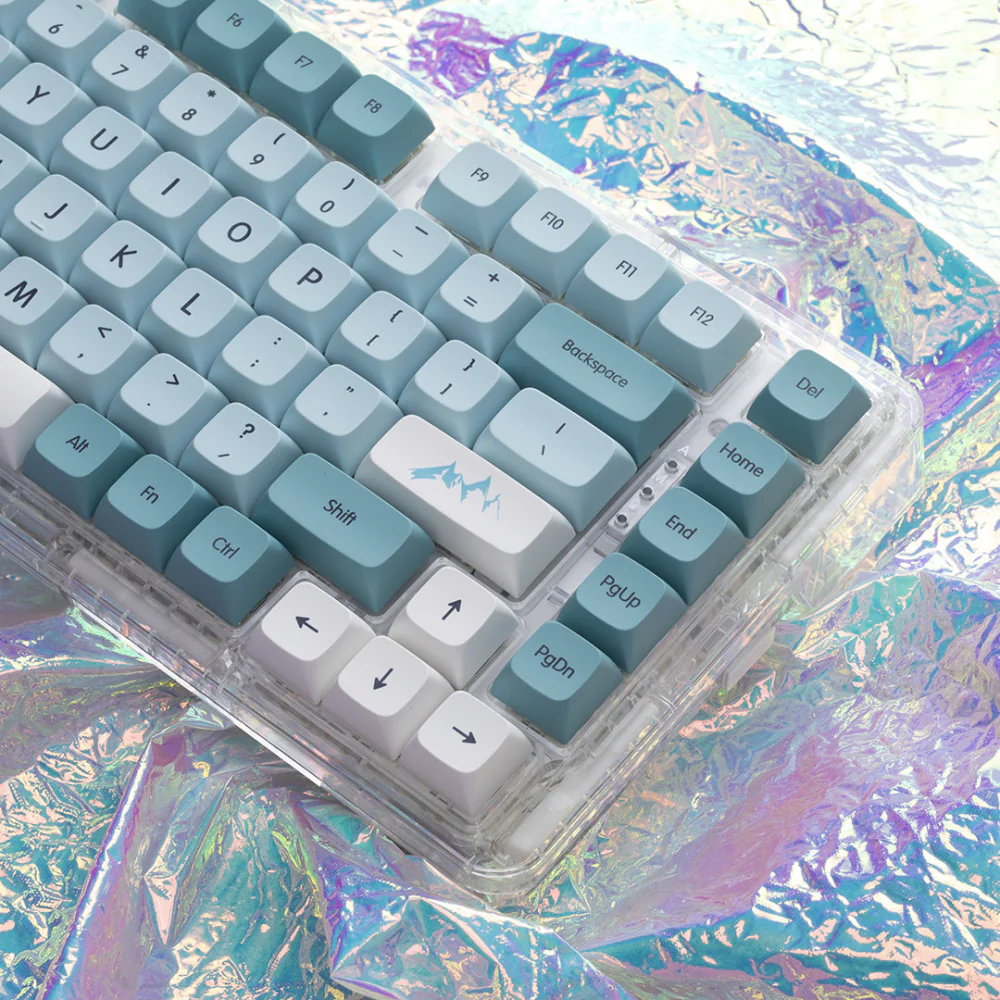 Blue and white XDA keycaps on a keyboard over a colorful iridescent surface