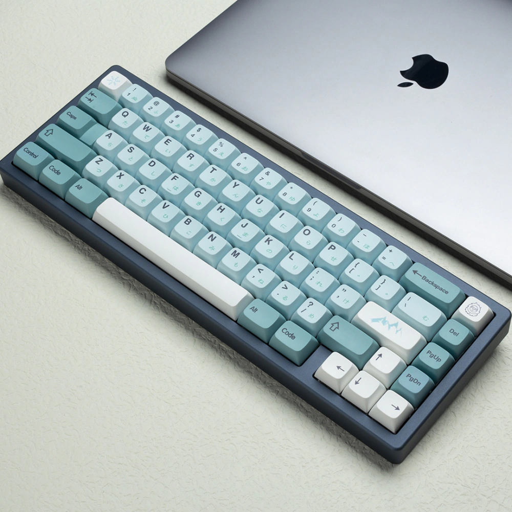 Blue and white keycaps on a compact keyboard placed next to a silver laptop