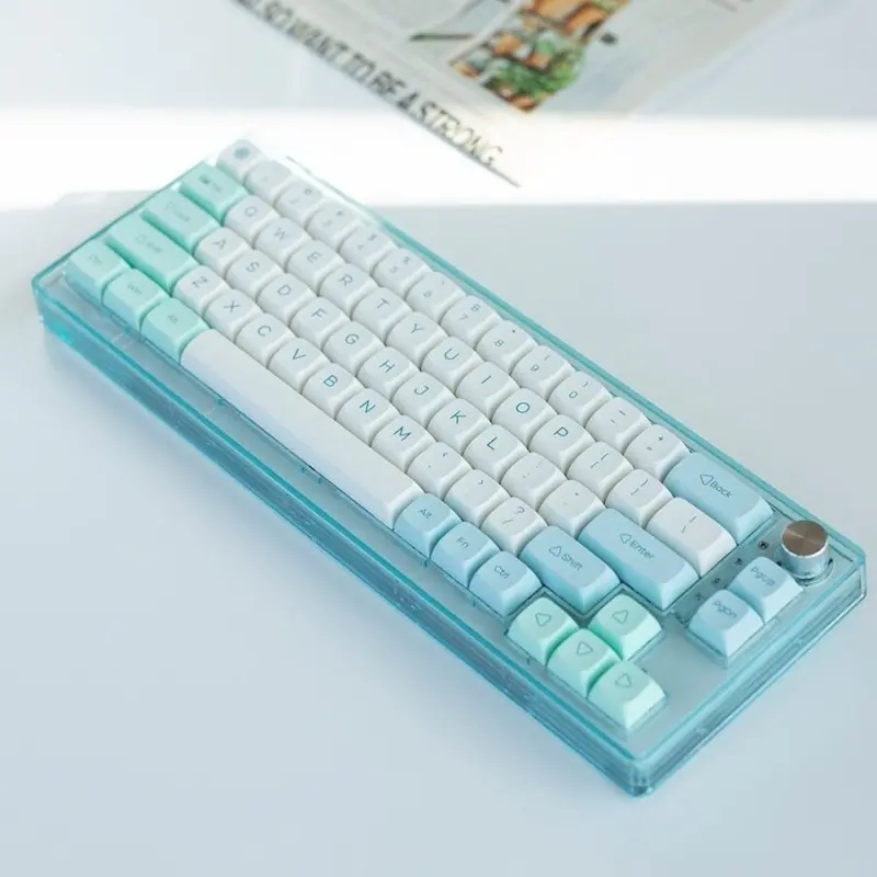 White and mint XDA keycaps on a translucent blue keyboard photographed from above.
