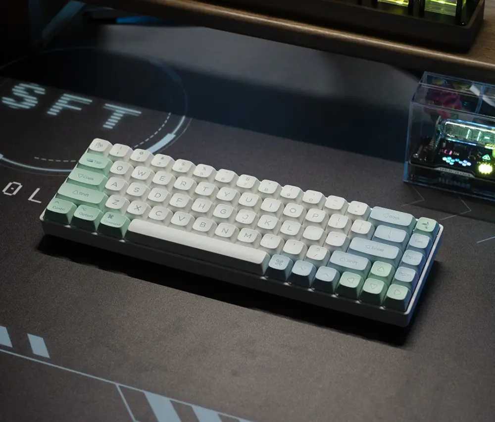 White and mint keycaps on a compact keyboard placed on a dark desk mat.