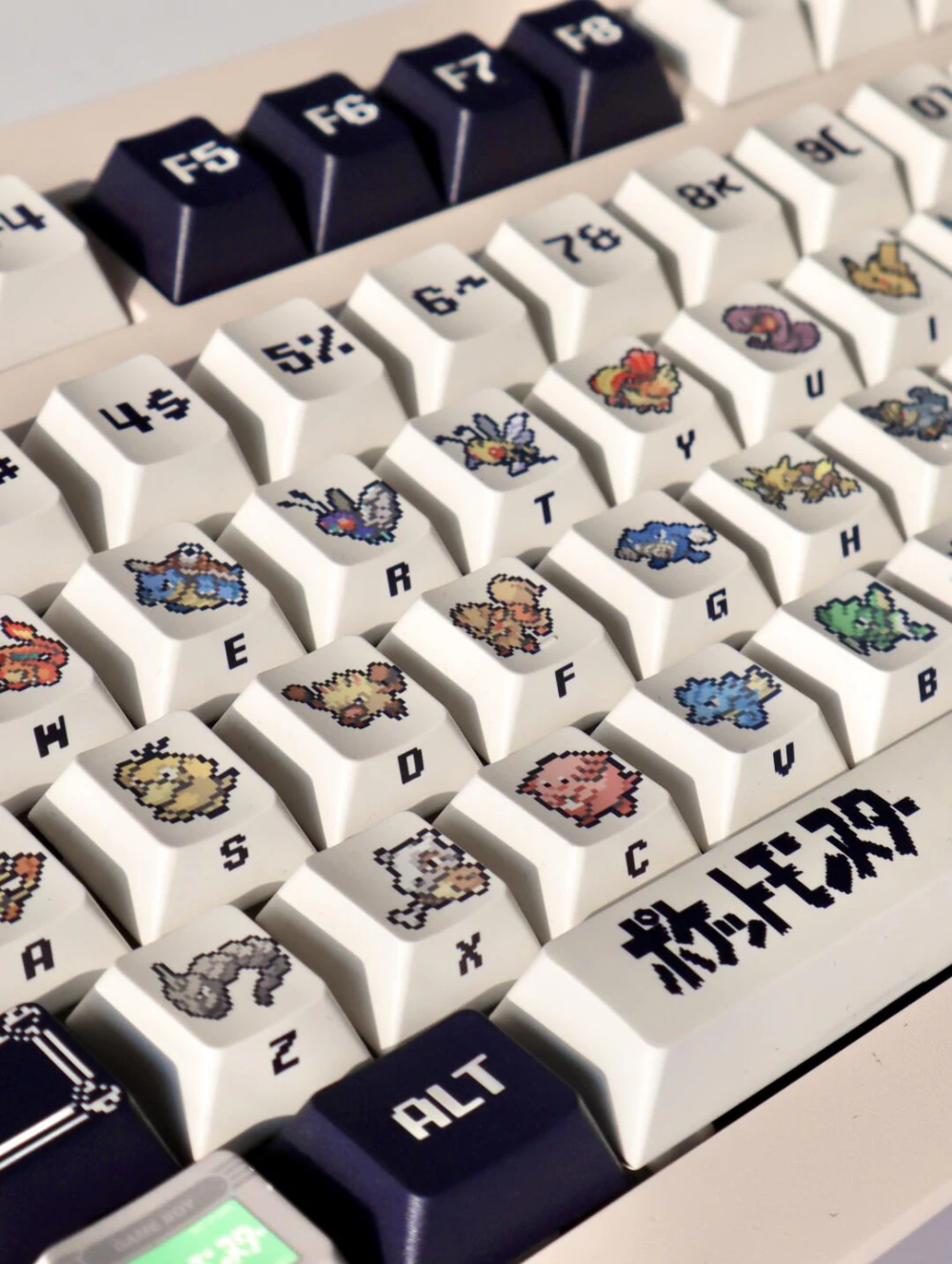 Mechanical keyboard with cream keycaps displaying retro red and green pixel artwork and dark accents.