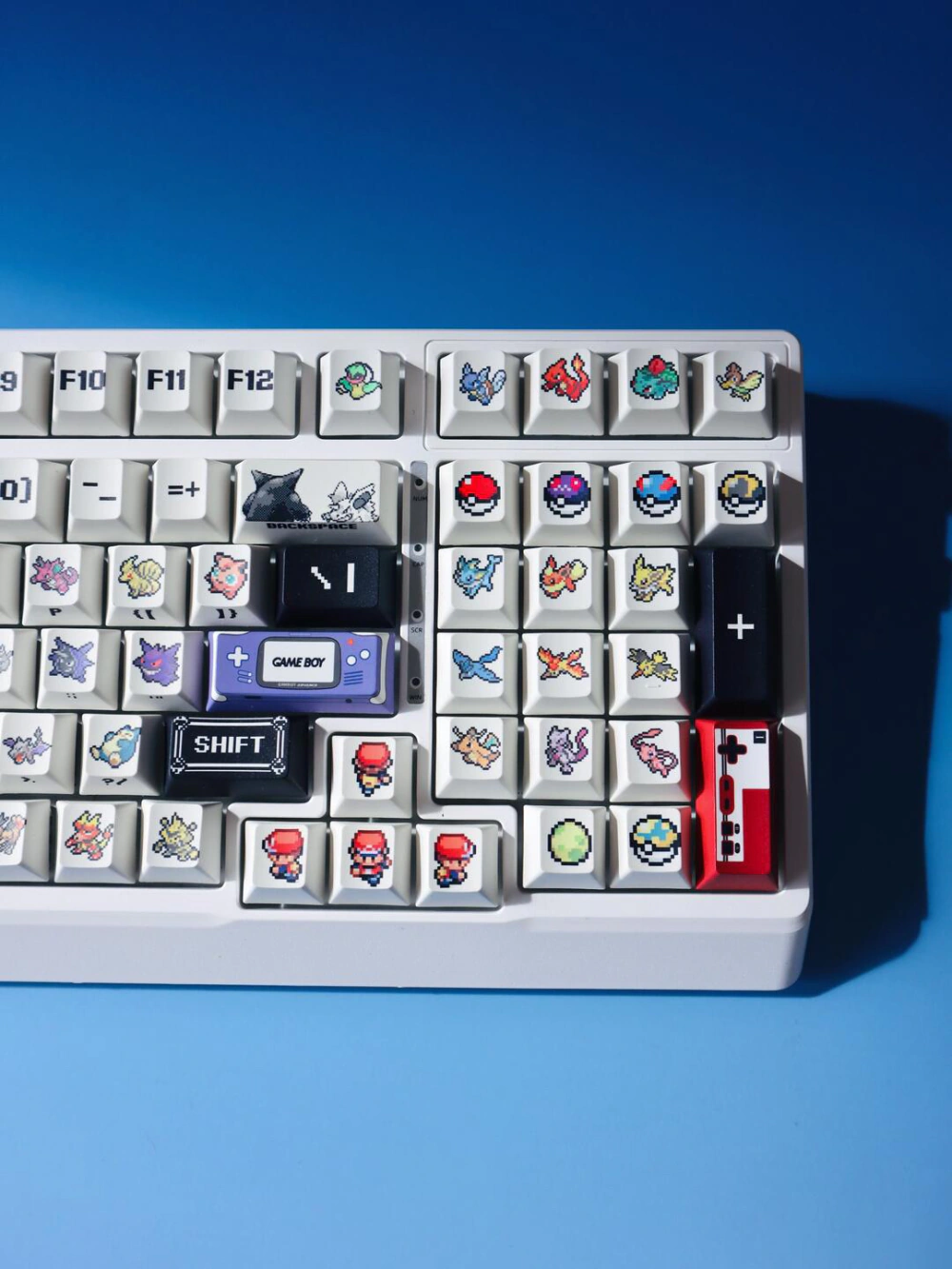 Retro red and green pixel keycaps with 8-bit icons and accent keys on a white mechanical keyboard.
