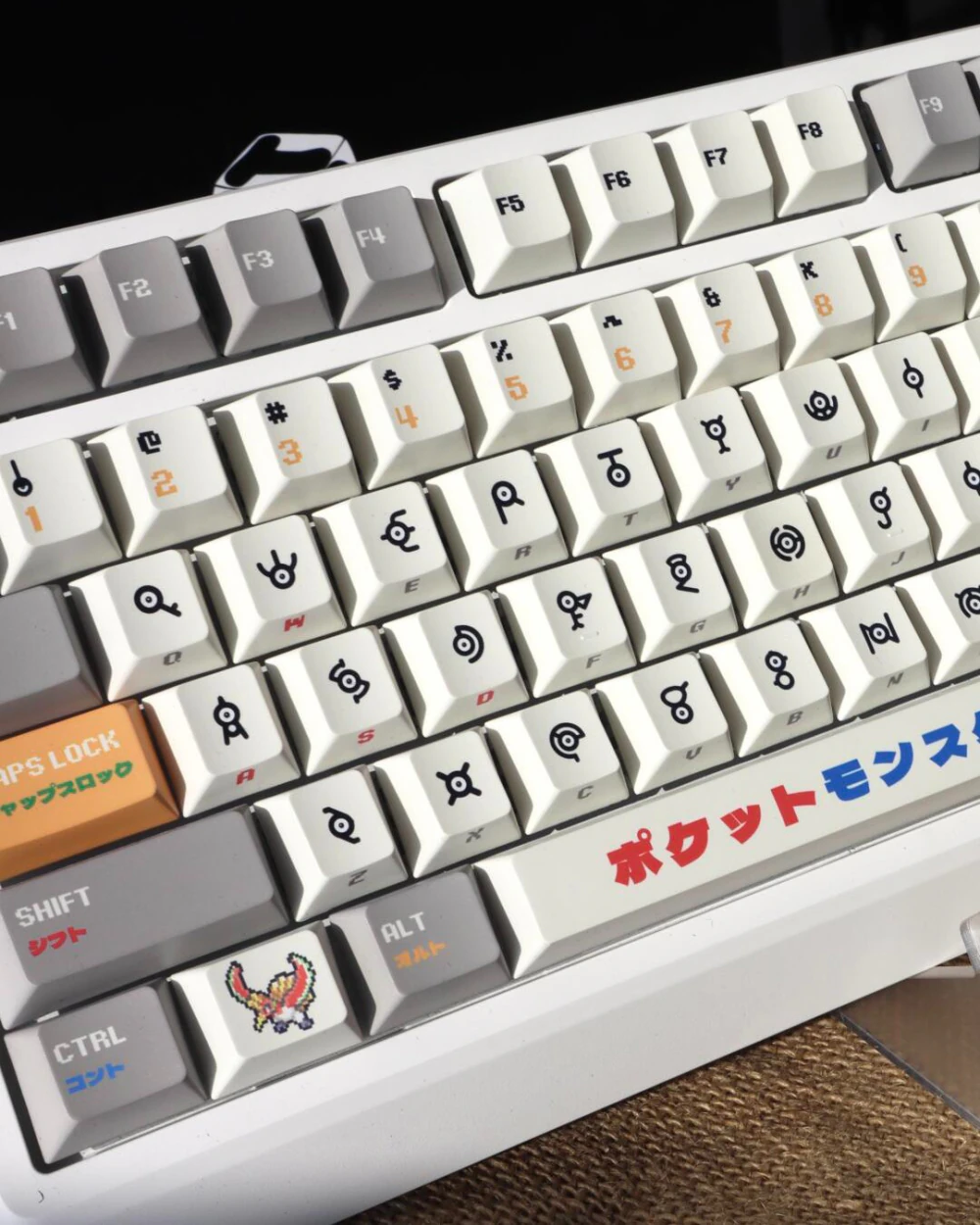 Diagonal close-up of retro gold silver pixel keycaps on white keyboard with Japanese spacebar and symbol legends.