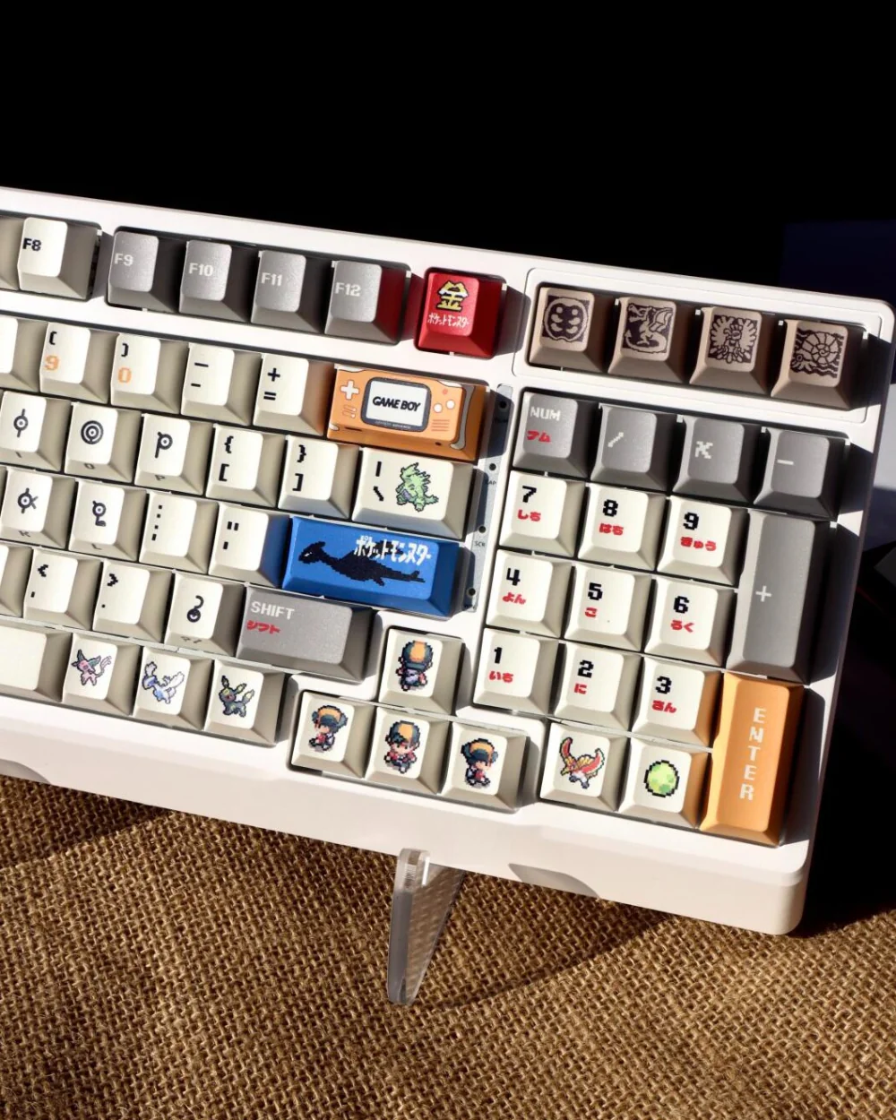 Retro gold silver pixel keycaps installed on white keyboard showing Japanese numpad and brown burlap background