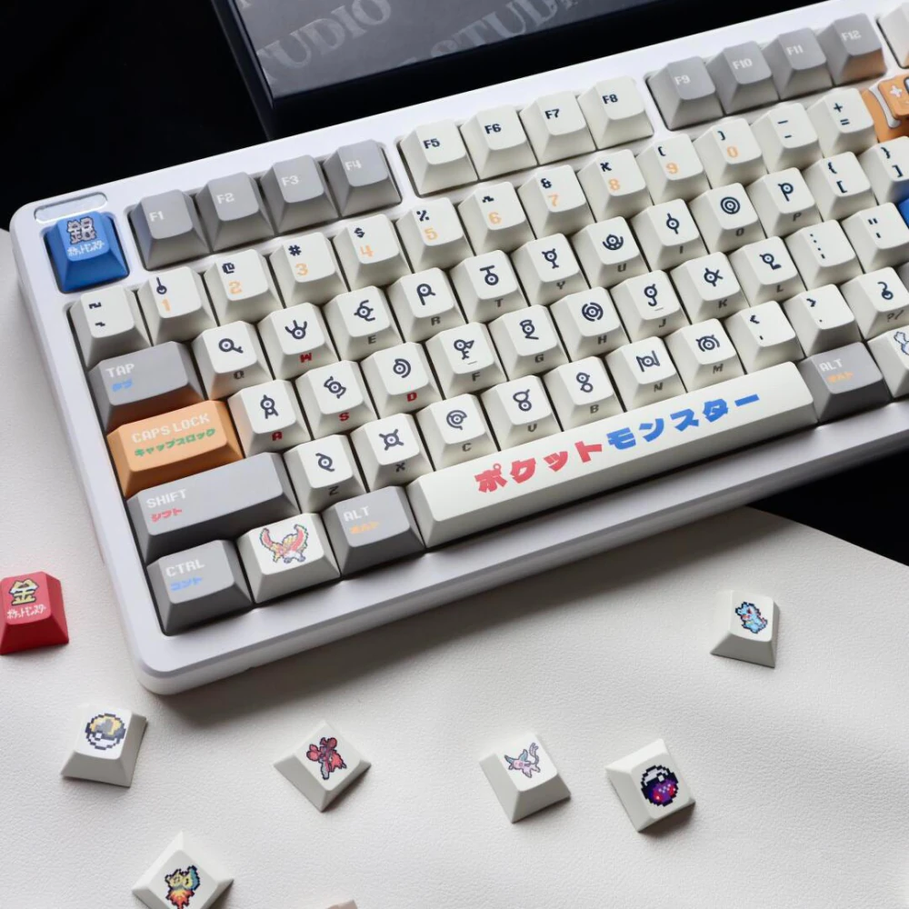 Retro gold silver pixel keycaps displayed on keyboard with scattered loose accent keys.