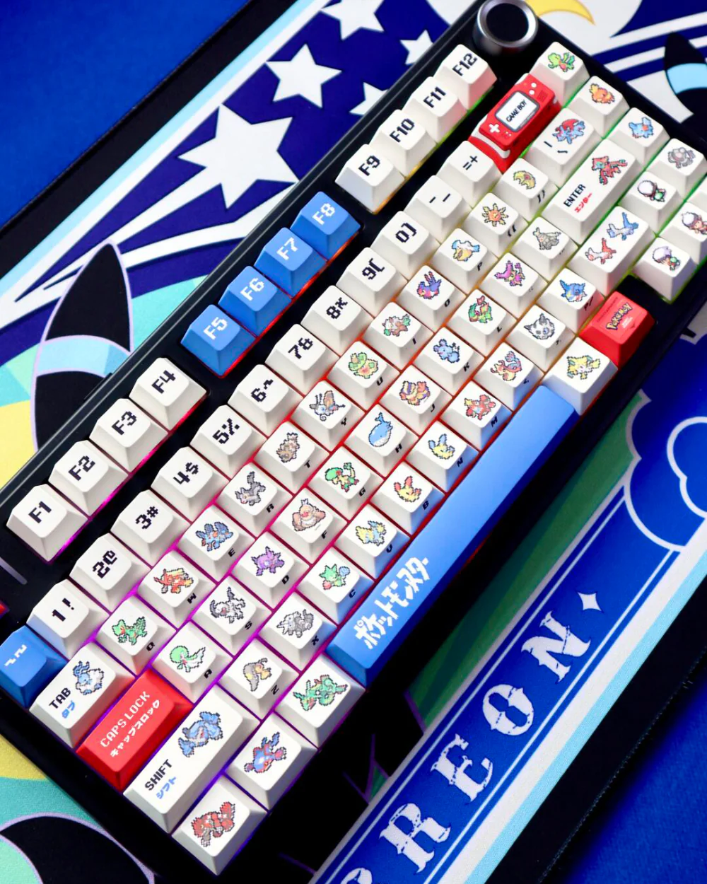 Black keyboard with retro ruby and sapphire pixel art keycaps and blue accents on starry desk mat.