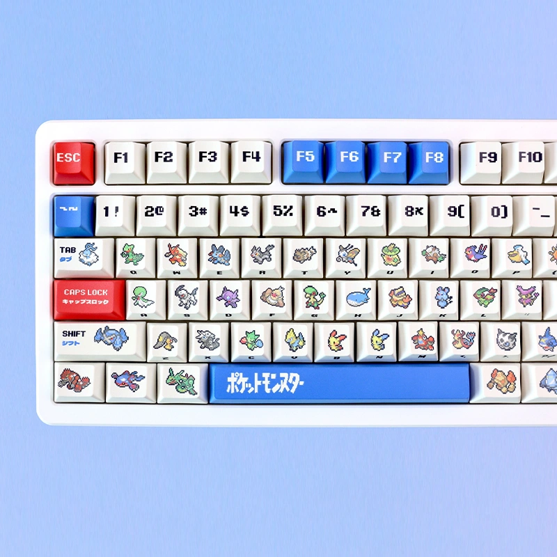 White keyboard left side with retro ruby and sapphire cherry profile pixel art keycaps and blue spacebar.