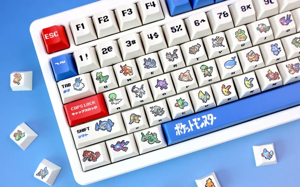 Cherry profile retro ruby and sapphire keycaps with pixel sprites on white keyboard and loose caps on blue.