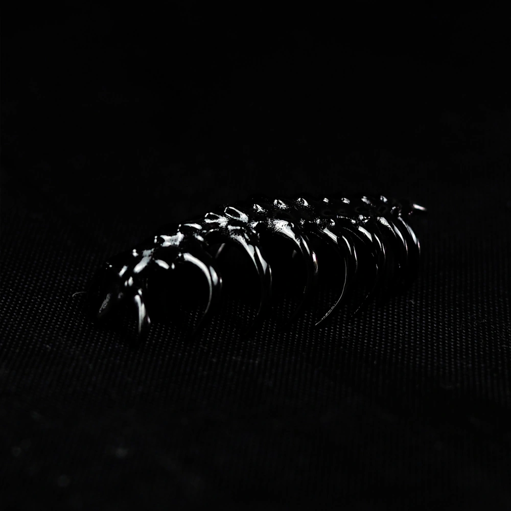Sci-Fi Creature Keycap Angled Studio Shot Handmade copper keycap sculpted as glossy black segmented creature on dark background.
