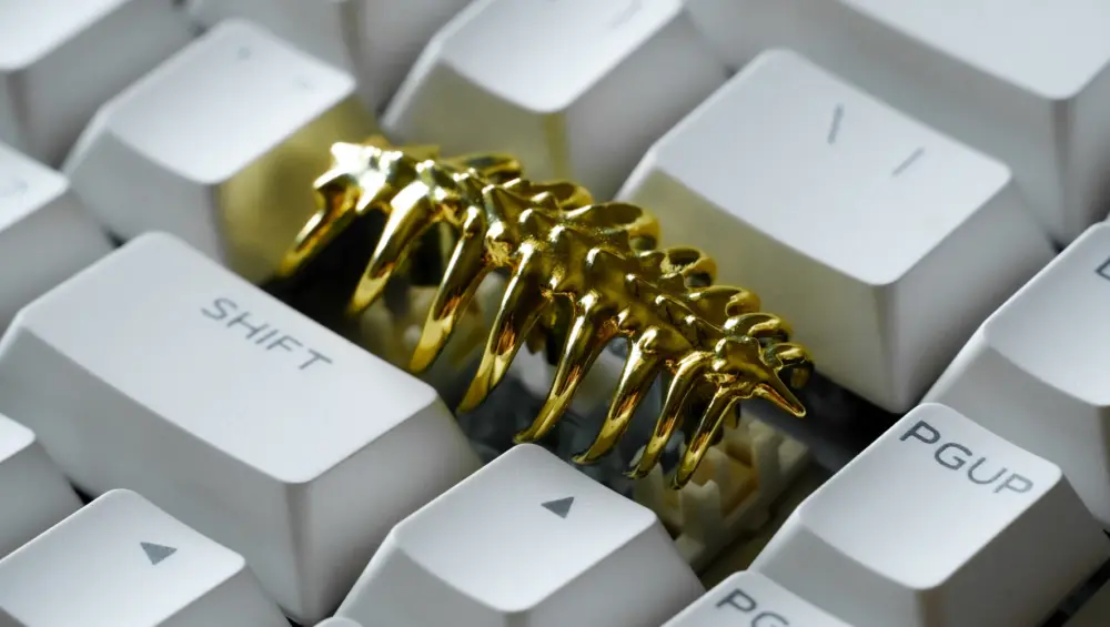 Sci-Fi Creature Gold Keycap Close Up Close-up of a gold creature shaped keycap installed among white keyboard keys.
