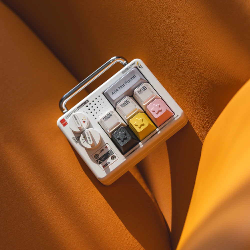 Black, yellow, and pink star keycaps on a compact display over orange fabric.
