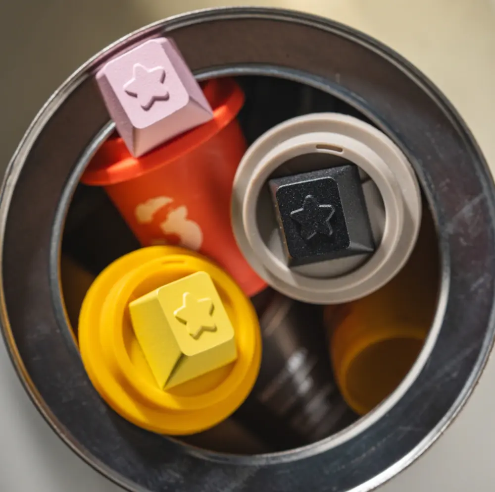 Black, yellow, and pink star themed keycaps displayed inside a round container.