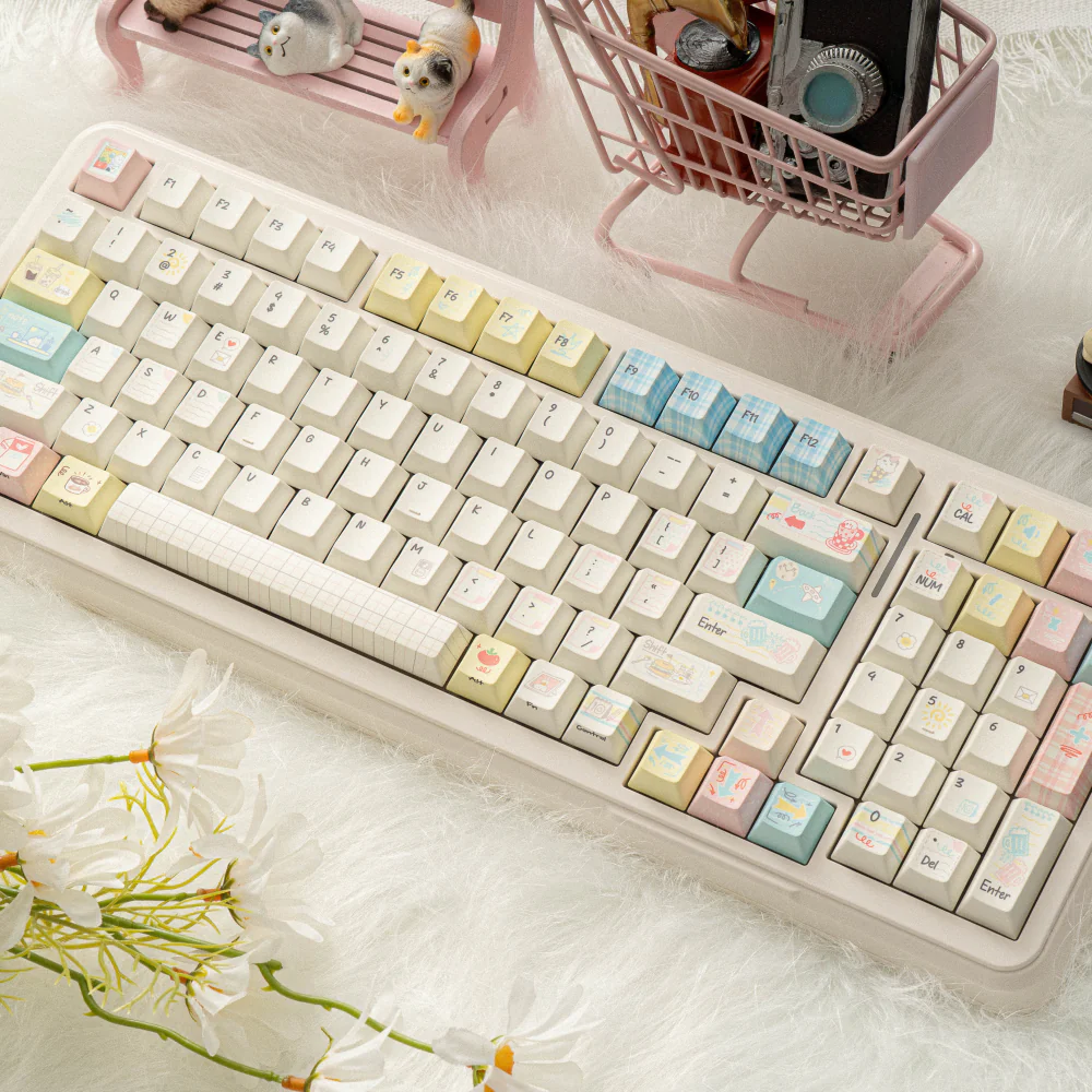 Angled close-up of a keyboard with Cozy Journal keycaps, white flowers, and pink accessories.