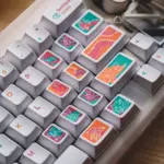 Close-up of colorful illustrated keycaps around the Enter and Backspace area of a white keyboard.
