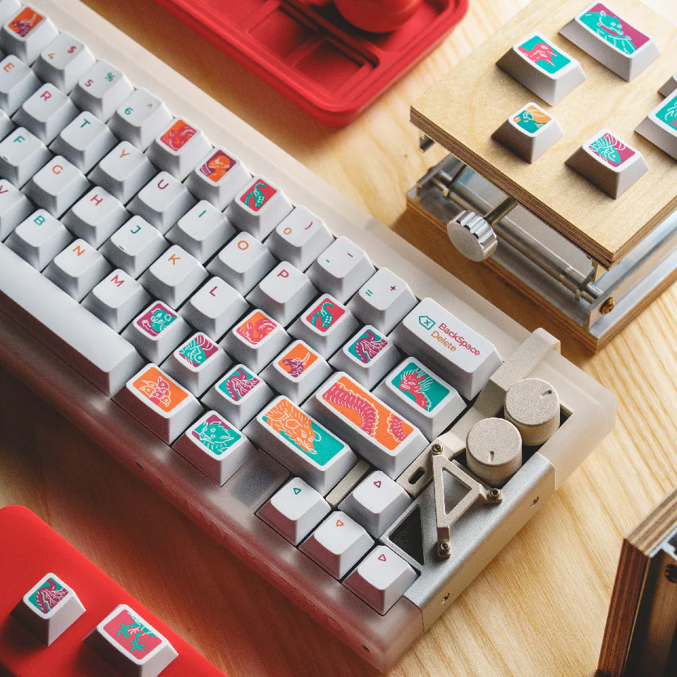 Right side of a white keyboard with colorful illustrated keycaps and several loose keys.