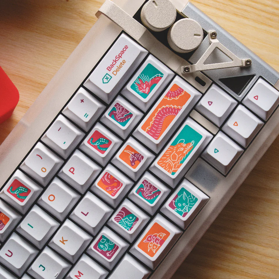Top right close-up of a white keyboard with illustrated keycaps beside two control knobs.