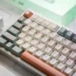 Close-up of white, gray-green, and salmon GUARDIAN keycaps installed on a keyboard.