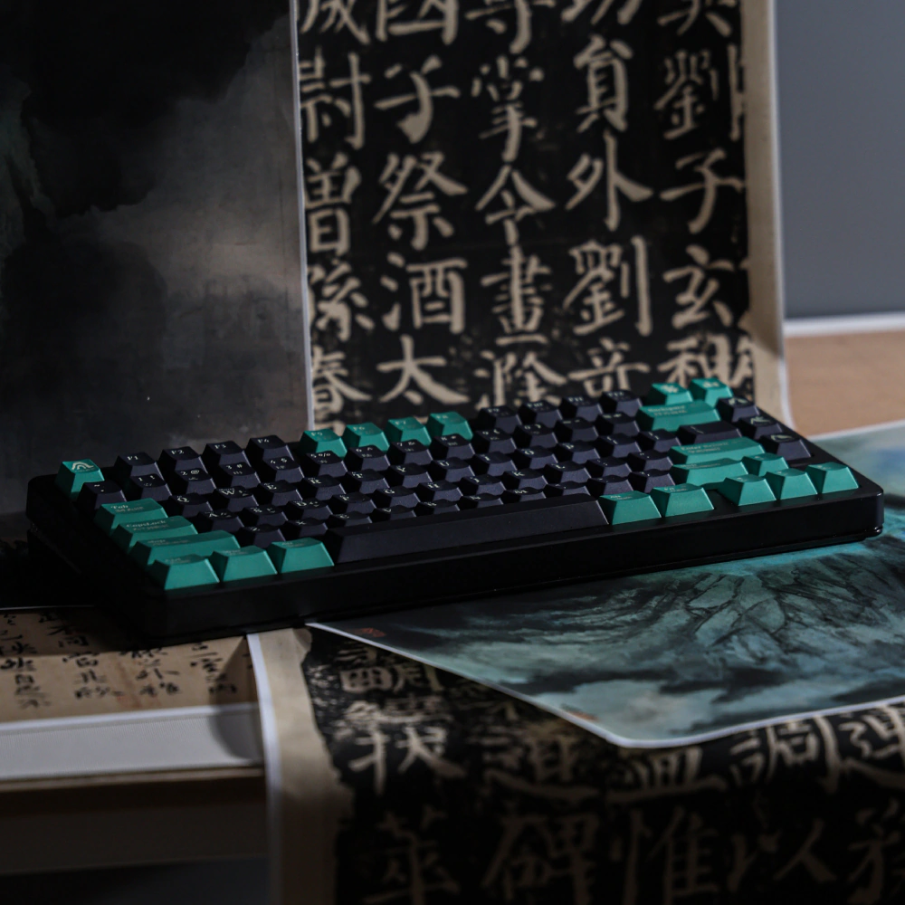 Full black keyboard with dark keys and sea-green modifiers on a desk.