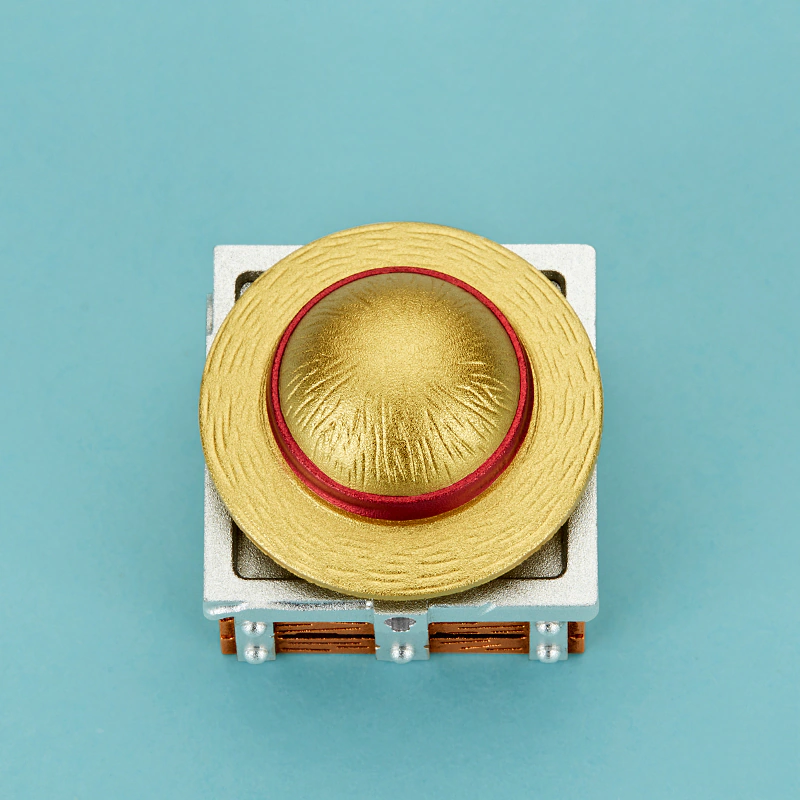 Rotating Straw Hat Aluminum Artisan Keycap Gold hat keycap with bright light shining through the metal base on a dark keyboard.