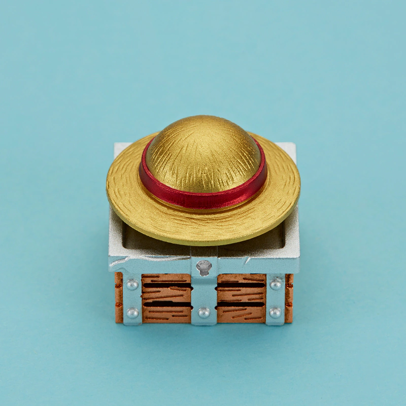 Rotating Straw Hat Aluminum Artisan Keycap Top view of a gold hat keycap with a red ring and textured surface.