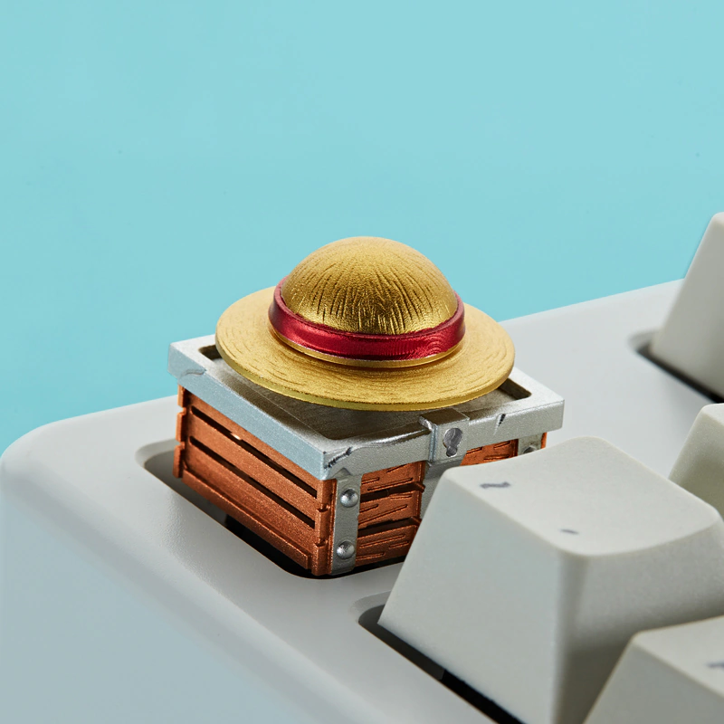 Gold and red hat keycap shown at an angle on a white mechanical keyboard.
