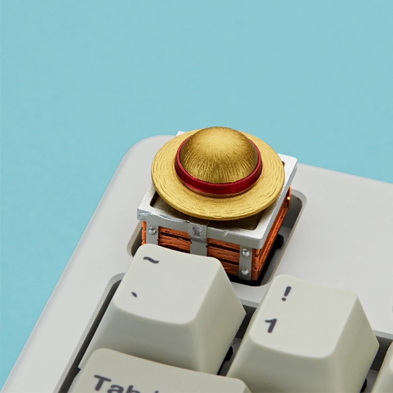 Gold hat keycap installed on a white mechanical keyboard.