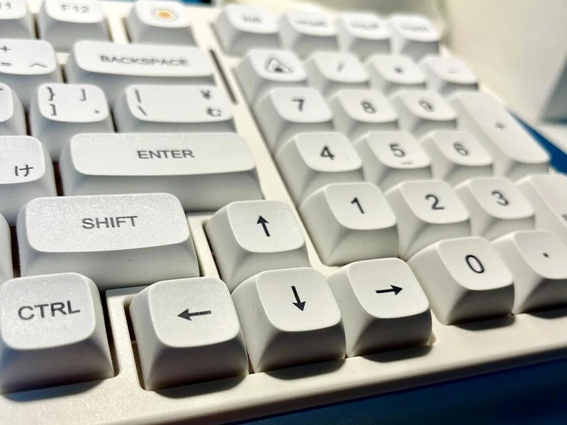 Close-up side view of white XDA profile keycaps showing the low uniform keycap shape on a mechanical keyboard