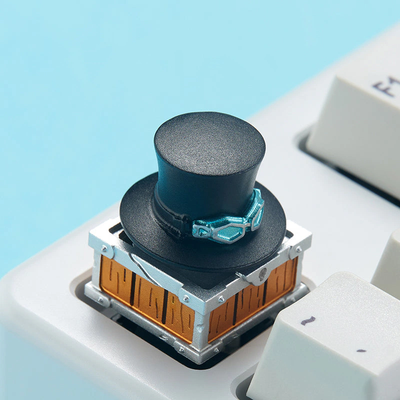 Sabo Rotating Hat Aluminum Artisan Keycap Angled view of a black top hat keycap with teal goggles on a keyboard.