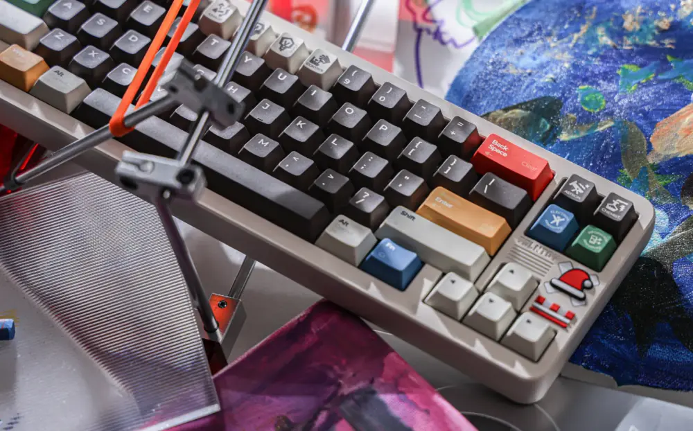 Keyboard at a diagonal angle with dark and gray keys, a red Backspace key, and blue and green accents.