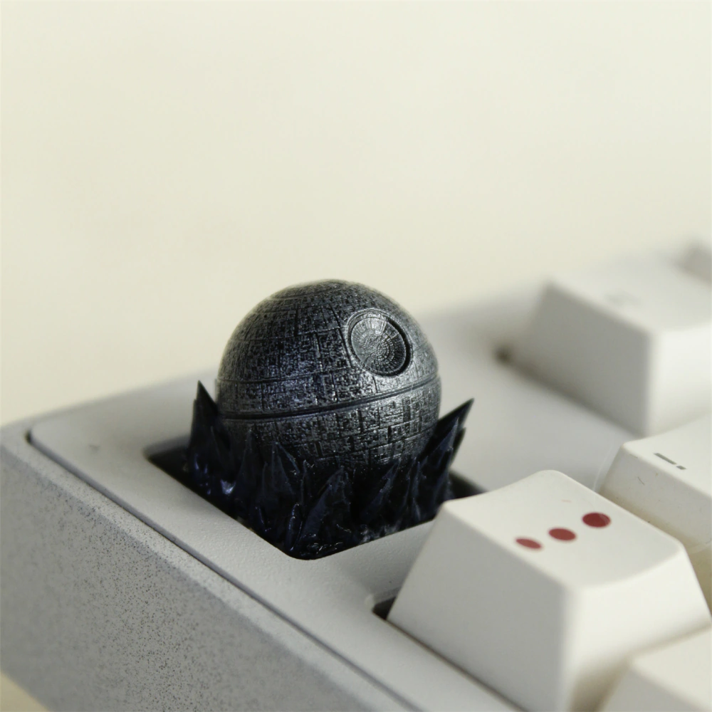 A gray paneled sphere is mounted in a pale keyboard, with its circular detail visible.